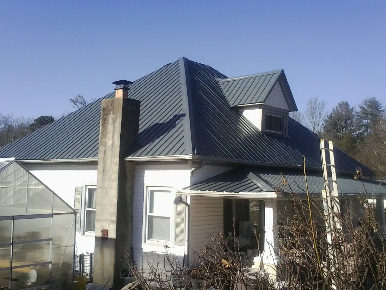 Dark blue standing seam metal roof on a white farmhouse with dormer — Slate & Tile Roof Repair by Roofing Brothers in Villas