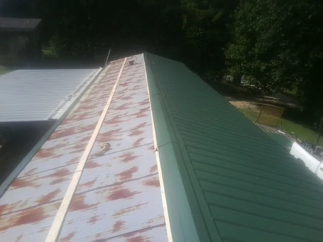 Old rusted panels beside newly installed green metal roofing — Wind Damage Roof Repair by Roofing Brothers in Villas