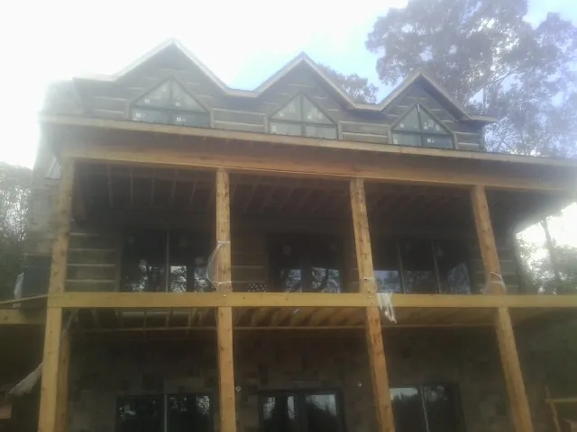 Dormers and porch framing on a large log home under construction — Roof Coating work by our crew in Villas
