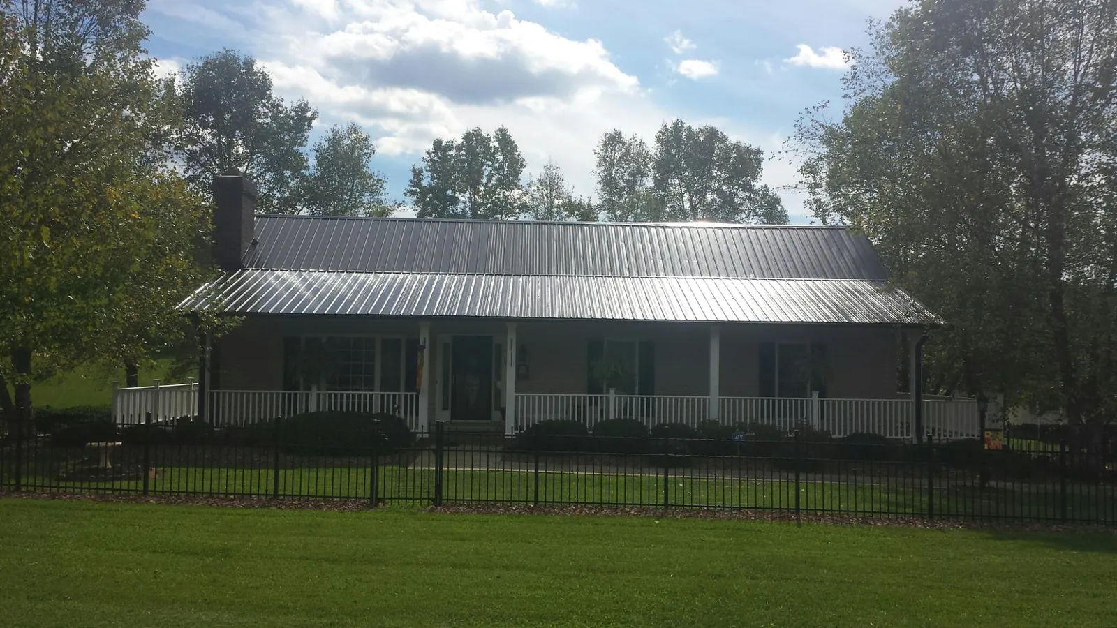 Gray metal roof on a brick ranch with a full width front porch — Gutter Guard Installation work by our crew in Villas