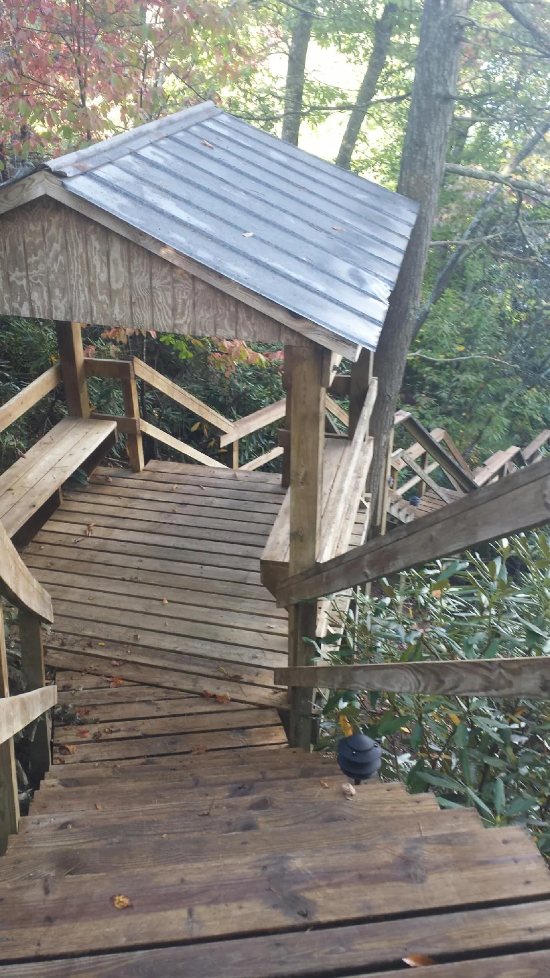 Metal roofed shelter over wooden steps on a wooded walkway — Skylight Repair & Installation work by our crew in Villas