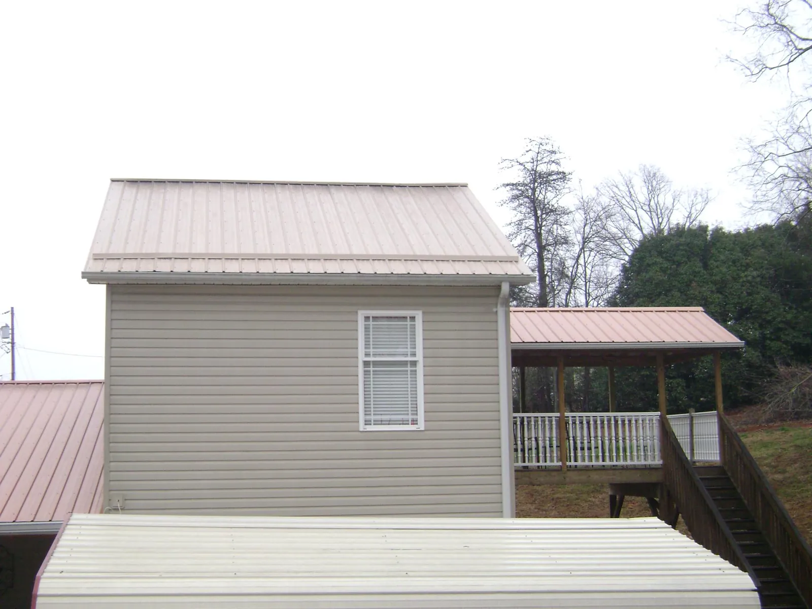 Tan metal roofs on a two story addition and attached porch, from a Roof Replacement job in Villas